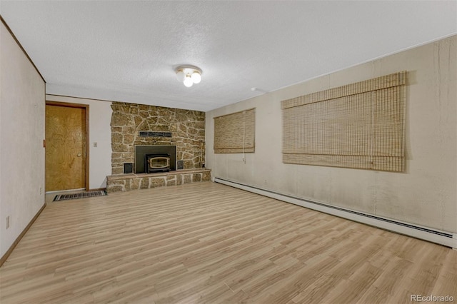 unfurnished living room with visible vents, a textured ceiling, a baseboard heating unit, and wood finished floors