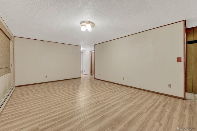 spare room featuring a textured ceiling, baseboard heating, light wood-type flooring, and baseboards