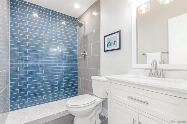 bathroom featuring a tile shower, toilet, oversized vanity, and tile floors