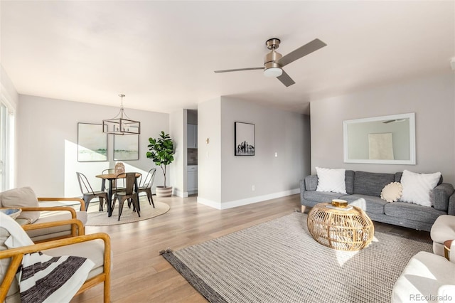 living room with ceiling fan with notable chandelier and hardwood / wood-style floors