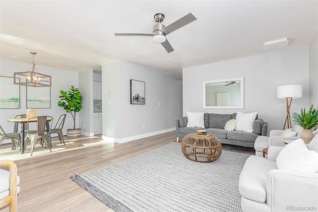 living room featuring ceiling fan with notable chandelier and hardwood / wood-style flooring