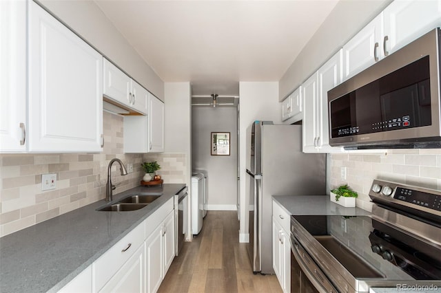 kitchen featuring white cabinetry, light wood-type flooring, stainless steel appliances, sink, and tasteful backsplash