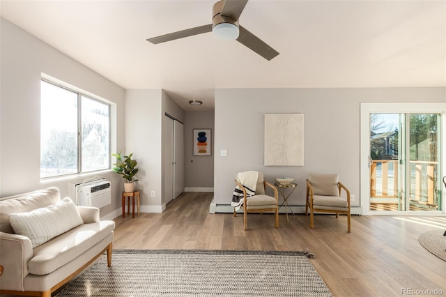 living room with a wall unit AC, light wood-type flooring, and ceiling fan