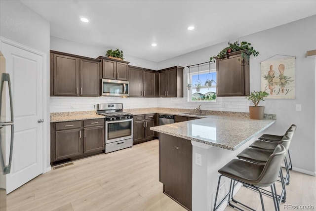 7218 Animas Ave, Frederick, CO 80530 - kitchen featuring stainless steel appliances, a sink, dark brown cabinetry, a peninsula, and decorative backsplash