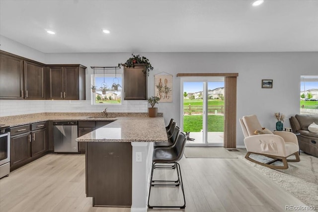 7218 Animas Ave, Frederick, CO 80530 - kitchen with appliances with stainless steel finishes, a sink, light wood finished floors, a kitchen breakfast bar, and recessed lighting