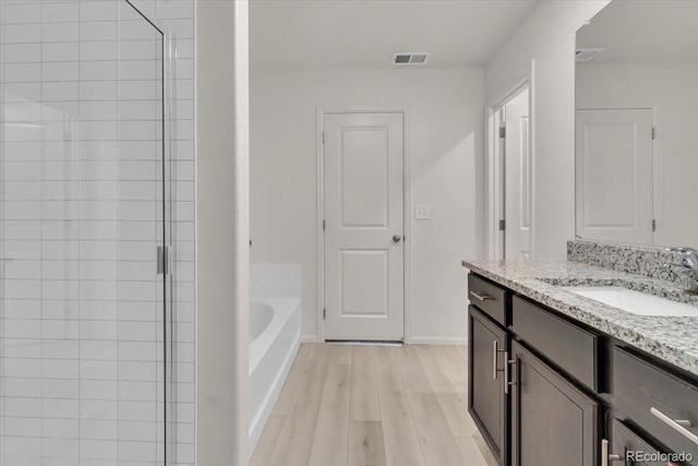 7218 Animas Ave, Frederick, CO 80530 - bathroom with vanity, a shower stall, a bath, wood finished floors, and baseboards