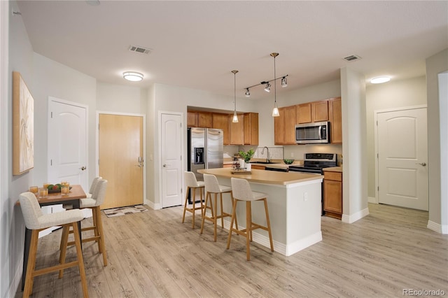 kitchen with stainless steel appliances, light wood-style floors, visible vents, and a sink