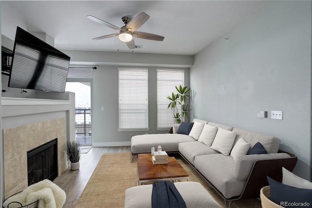 living room with light wood finished floors, plenty of natural light, a ceiling fan, and a tile fireplace