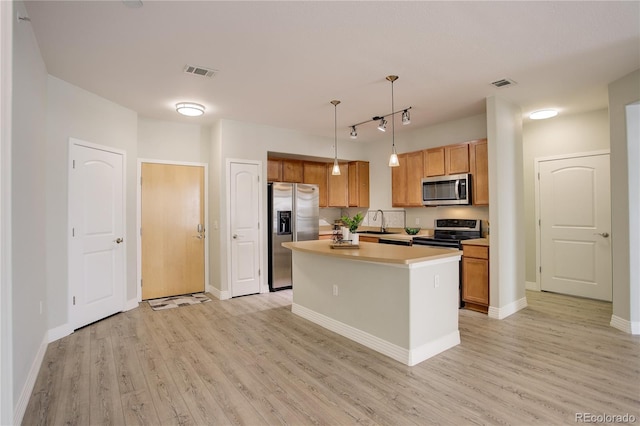 kitchen with appliances with stainless steel finishes, light wood-type flooring, visible vents, and a sink