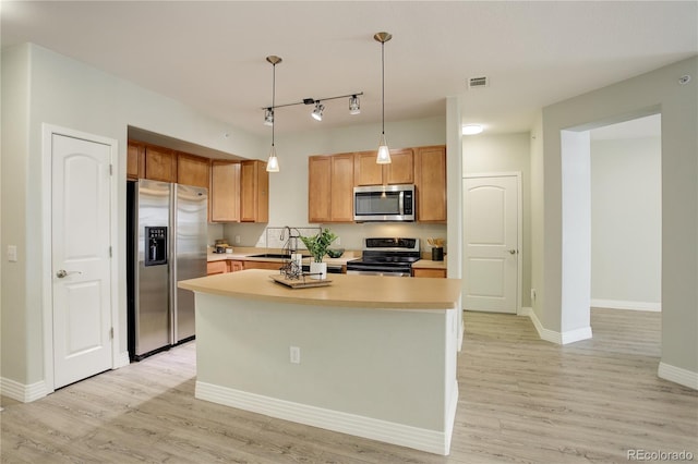 kitchen featuring light wood-style flooring, a kitchen island, appliances with stainless steel finishes, and light countertops