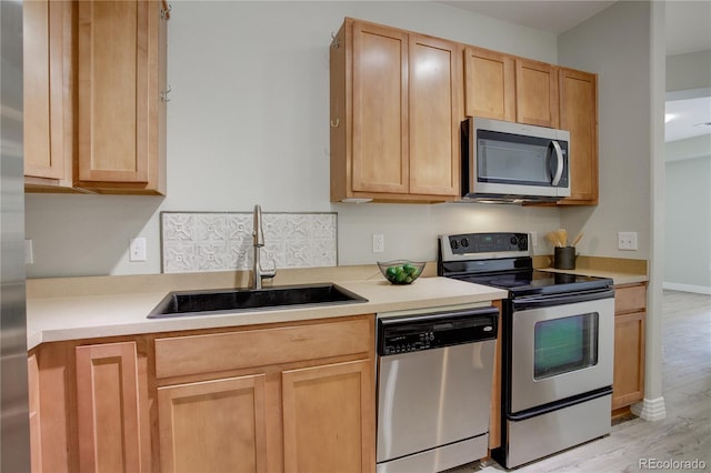 kitchen featuring light brown cabinets, stainless steel appliances, and a sink