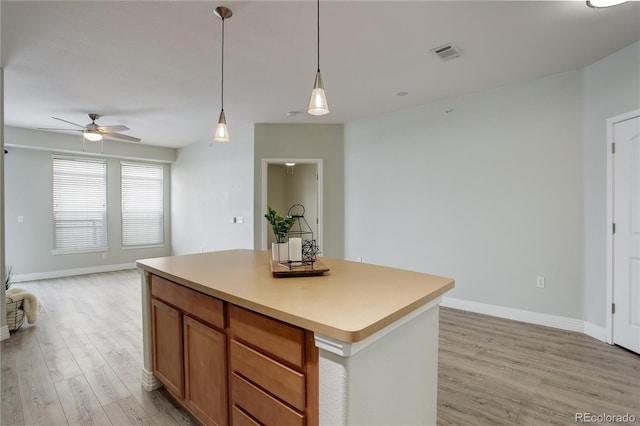 kitchen with visible vents, open floor plan, a center island, light wood-style floors, and pendant lighting