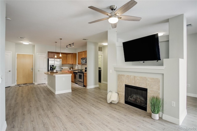 kitchen with appliances with stainless steel finishes, open floor plan, a sink, and light wood-style flooring