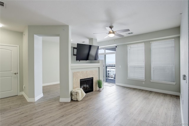 living room featuring visible vents, ceiling fan, wood finished floors, a tile fireplace, and baseboards