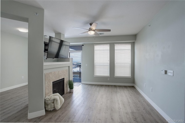 unfurnished living room with a fireplace, wood finished floors, a ceiling fan, visible vents, and baseboards