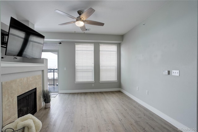 living area featuring visible vents, baseboards, a ceiling fan, a tile fireplace, and light wood-style flooring