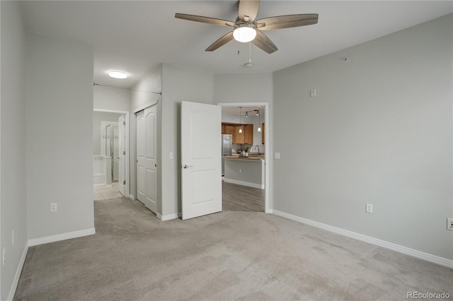 spare room featuring ceiling fan, baseboards, and light colored carpet