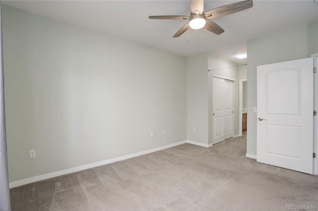 carpeted empty room with a ceiling fan and baseboards