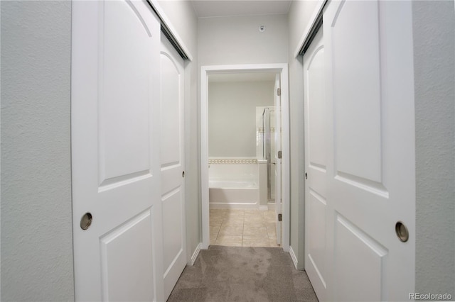 hall featuring tile patterned flooring and carpet flooring