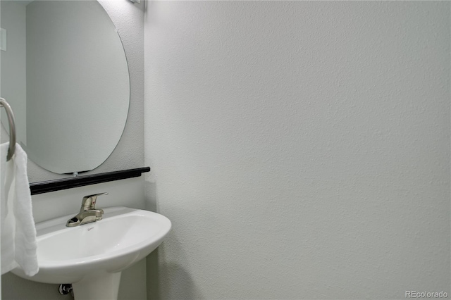 bathroom featuring a textured wall and a sink