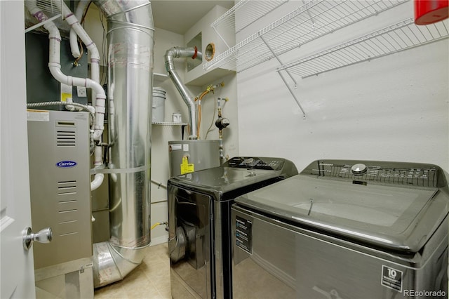 laundry room with heating unit, water heater, laundry area, independent washer and dryer, and tile patterned floors