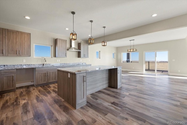 kitchen with dark hardwood / wood-style flooring, decorative light fixtures, light stone countertops, and a kitchen island