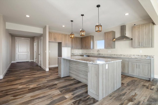 kitchen with light stone counters, decorative light fixtures, a center island, dark hardwood / wood-style floors, and wall chimney range hood