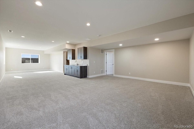 unfurnished living room with light colored carpet and sink