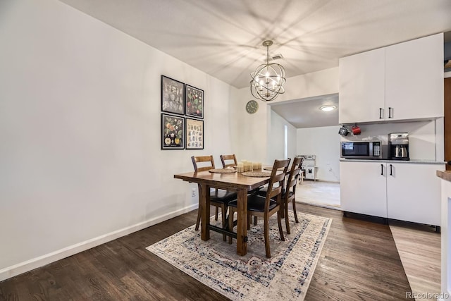 dining area with dark hardwood / wood-style flooring and an inviting chandelier