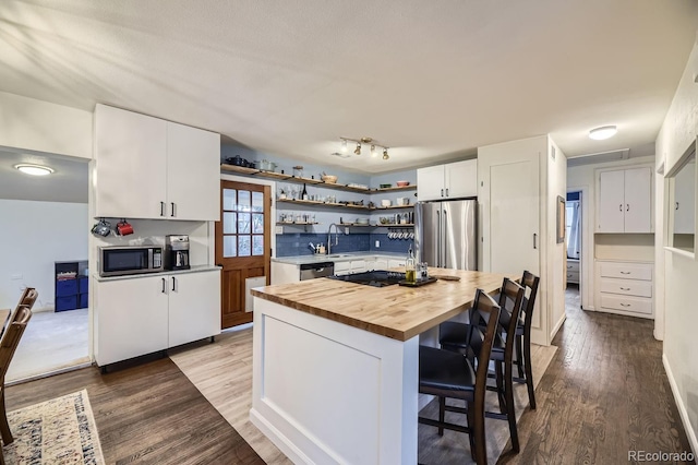 kitchen with sink, white cabinetry, wooden counters, appliances with stainless steel finishes, and a kitchen island