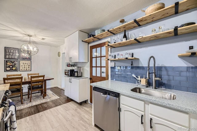 kitchen with sink, white cabinetry, stainless steel dishwasher, pendant lighting, and light hardwood / wood-style floors