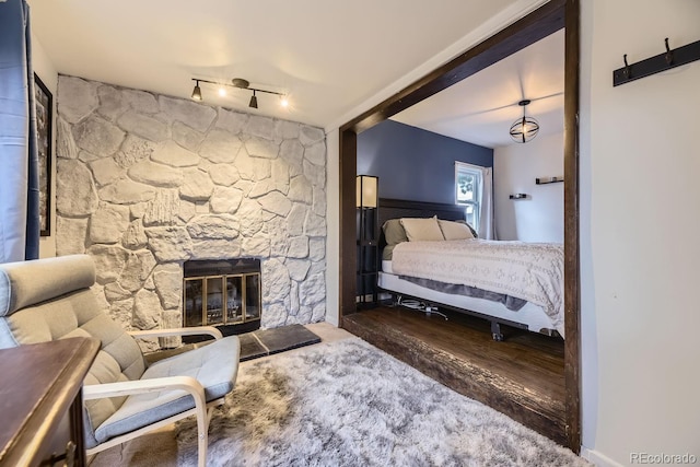 bedroom featuring rail lighting, dark hardwood / wood-style floors, and a fireplace