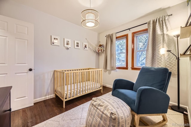 bedroom with dark hardwood / wood-style flooring and a crib