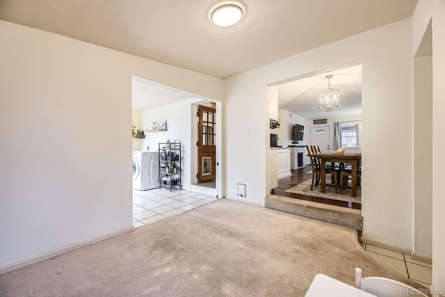 interior space featuring light colored carpet, washer / clothes dryer, and a chandelier