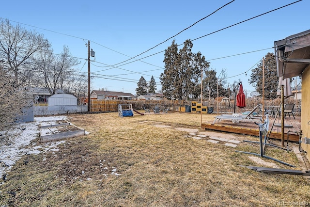 view of yard featuring a shed, a playground, and a deck