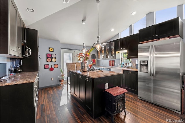 kitchen featuring appliances with stainless steel finishes, a kitchen island, hanging light fixtures, vaulted ceiling, and dark hardwood / wood-style floors