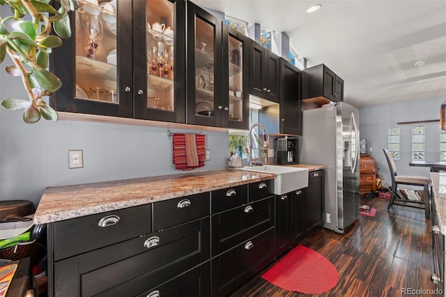 kitchen with sink, light stone counters, appliances with stainless steel finishes, and dark hardwood / wood-style flooring