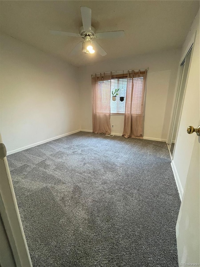 unfurnished room featuring ceiling fan and dark carpet