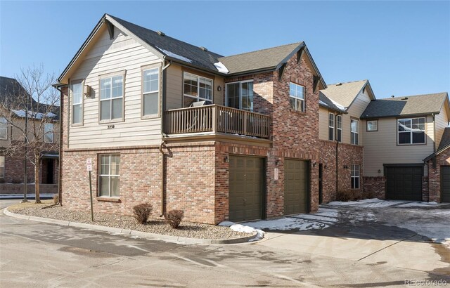 2250 S Vaughn Way Unit 204, Aurora, CO 80014 - view of front of home with an attached garage, a balcony, brick siding, and driveway