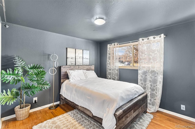 bedroom with a textured ceiling and hardwood / wood-style flooring