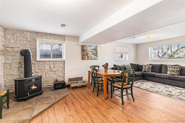 dining room with light hardwood / wood-style floors and a wood stove