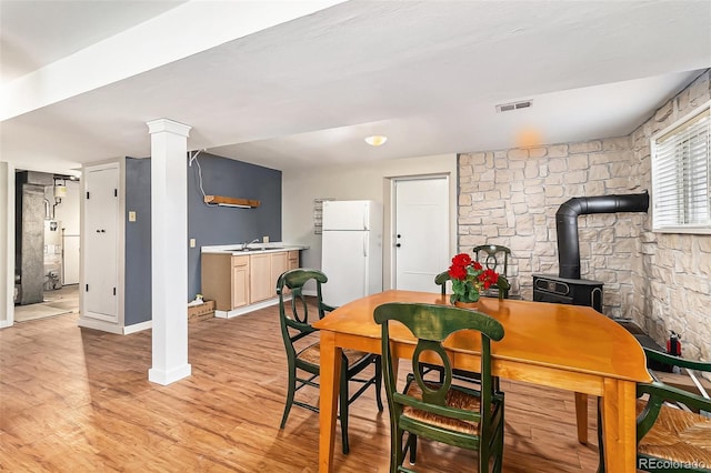 dining room featuring a wood stove, gas water heater, light hardwood / wood-style flooring, and sink