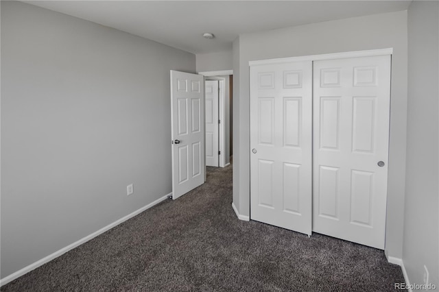 unfurnished bedroom featuring a closet and dark colored carpet