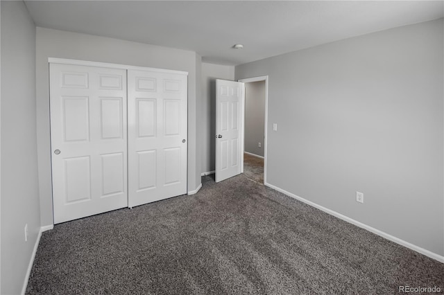 unfurnished bedroom with dark carpet and a closet