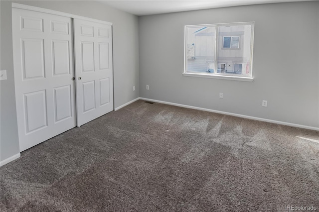 unfurnished bedroom featuring dark carpet and a closet