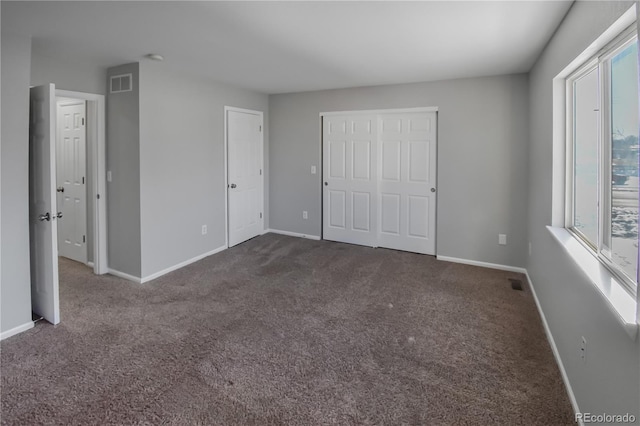 unfurnished bedroom with dark carpet and a closet