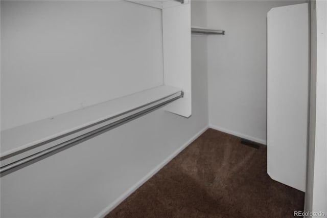 walk in closet with dark colored carpet