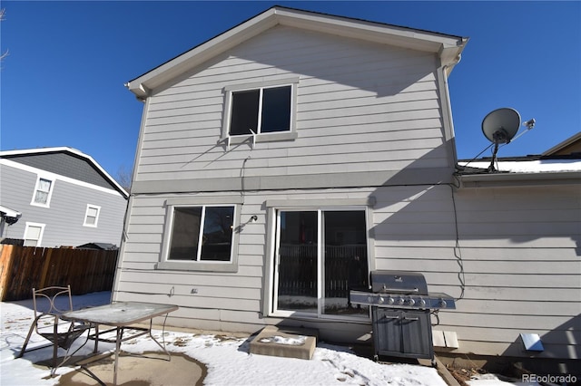 snow covered rear of property with a patio