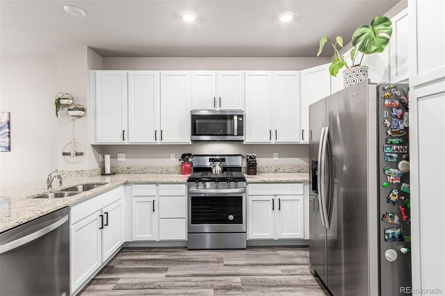 5187 S Fairplay St, Aurora, CO 80015 - kitchen with recessed lighting, white cabinetry, light stone counters, a sink, and stainless steel appliances