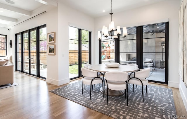 dining space with beamed ceiling, light hardwood / wood-style floors, and a chandelier